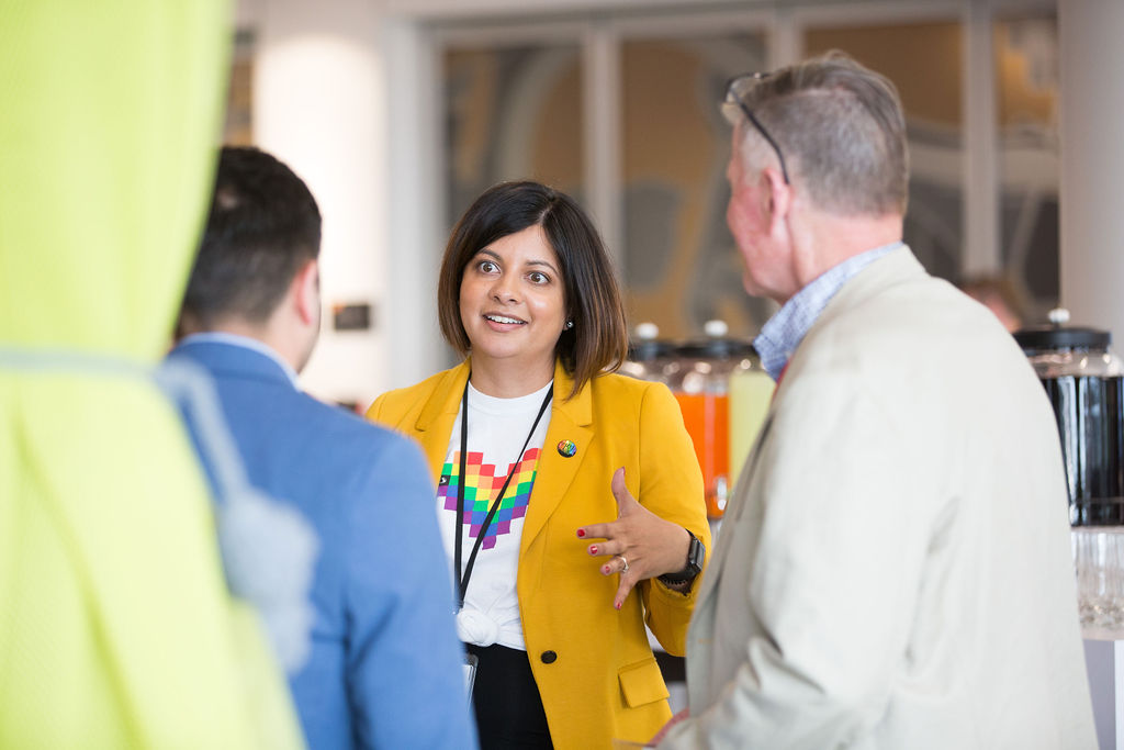 Photo of a professionally dresed woman animatedly speaking to two men